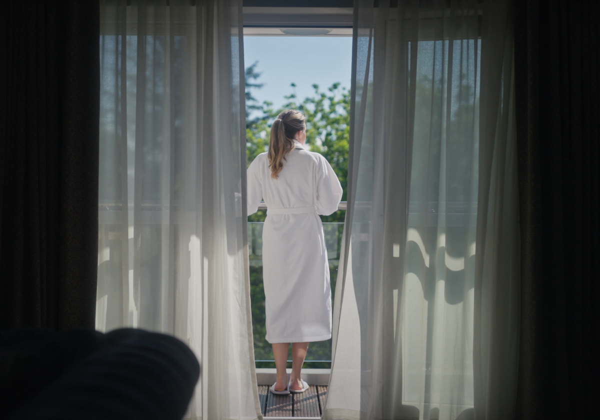 Guest, standing in the balcony of the Garden suite enjoying the garden view of The Killarney Park.
