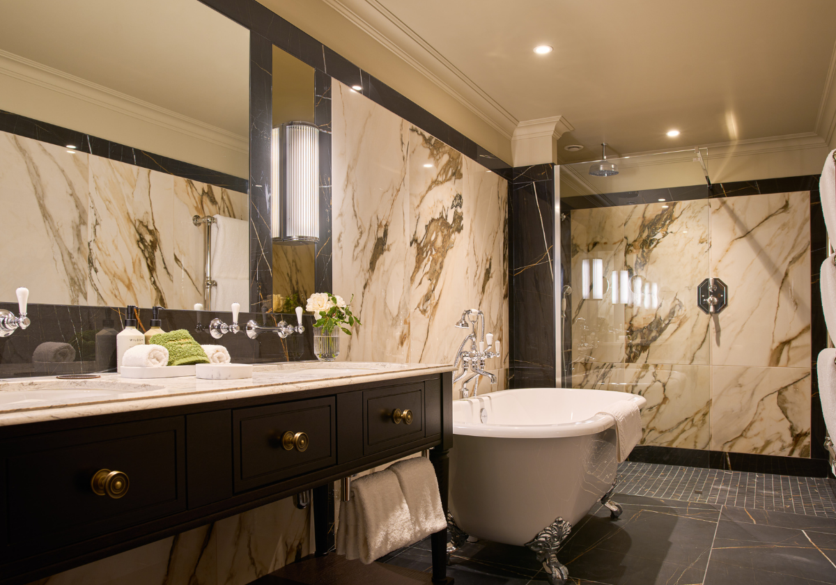 Elegant and	Modern suite bathroom with warm lighting, glass shower enclosure, dual vanity, claw foot bath tub, premium toiletries and minimalist décor.