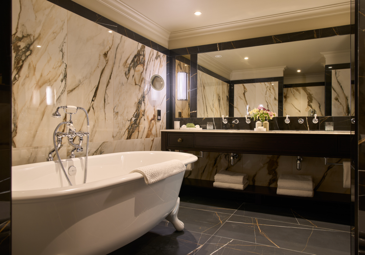 A luxurious ensuite bathroom with marble countertop, dual vanity and claw foot bathtub.