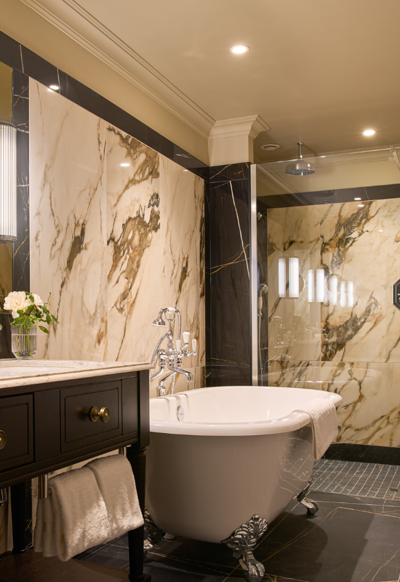 Elegant and	Modern suite bathroom with warm lighting, glass shower enclosure, claw foot bath tub and minimalist decor.