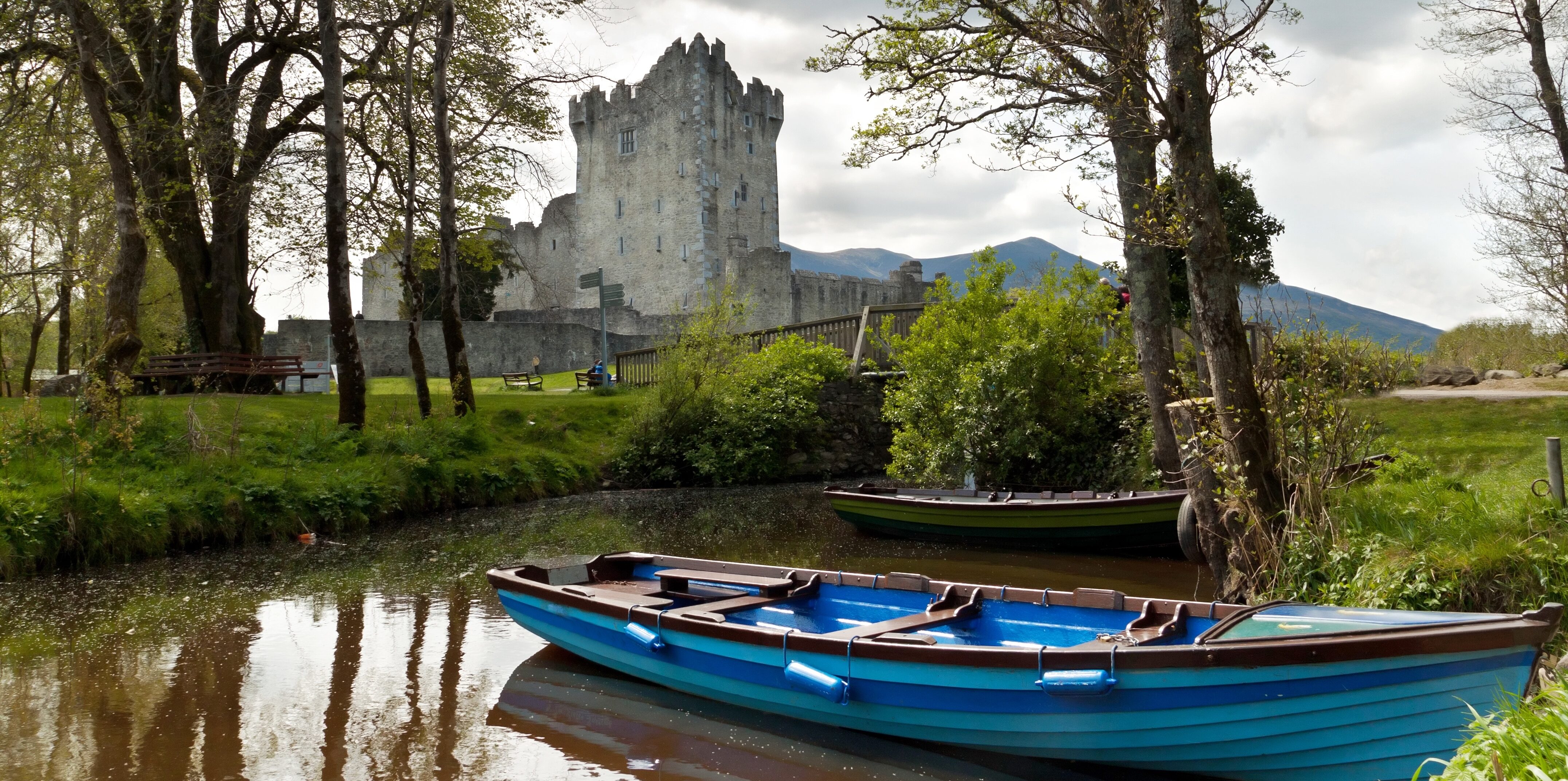 A blue rowing boat by the lake in front of The Ross Castle.