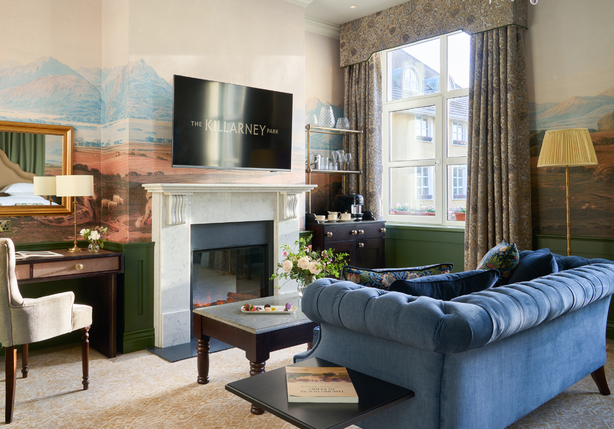A comfortable blue couch by the fireplace in the living area of The Signature Suite.