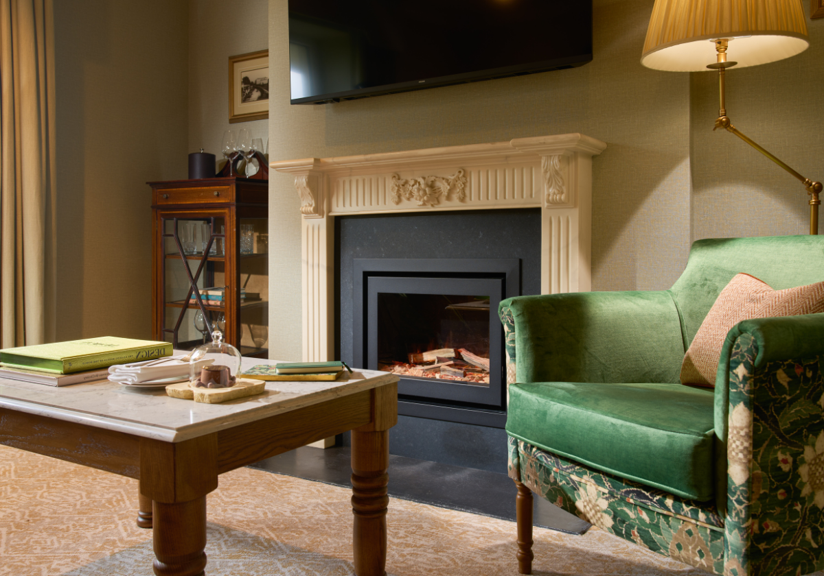 Green accent chair, fireplace and welcome cake for the guest in the living room of Guest Suite.